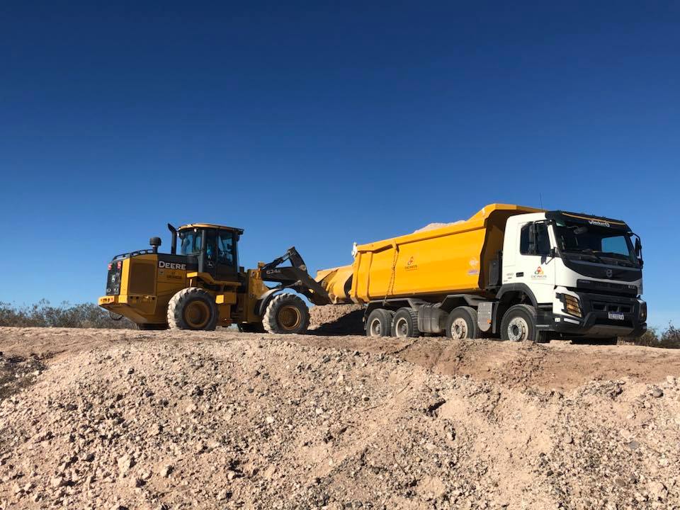 Retroexcavadora llenando batea de camion volcador en Deinos SRL