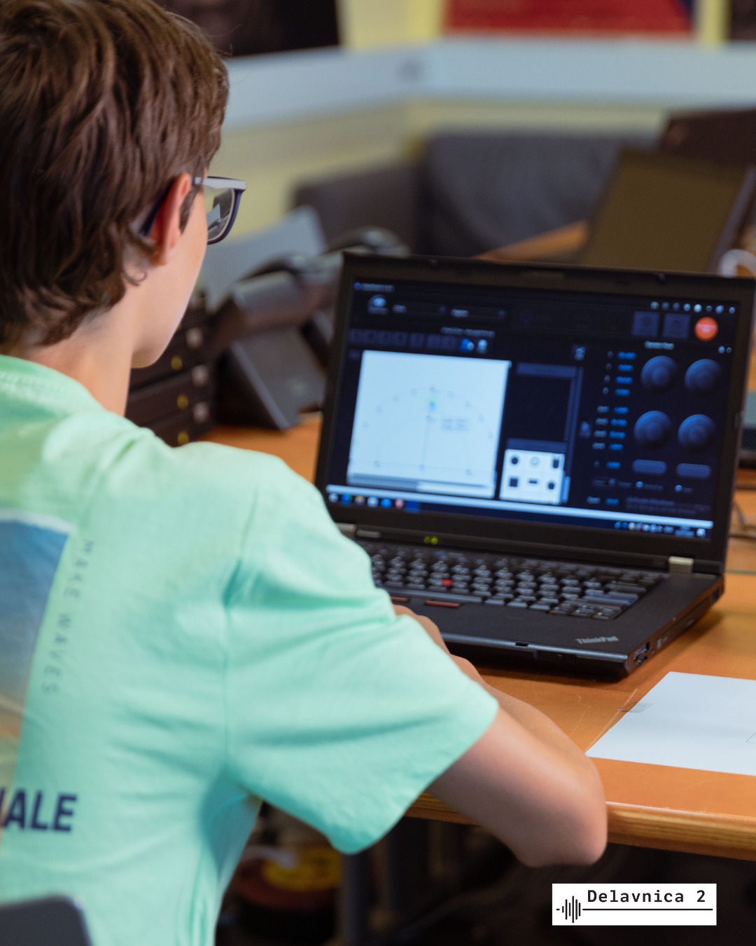 A pupil looking at a laptop screen where robots are controlled