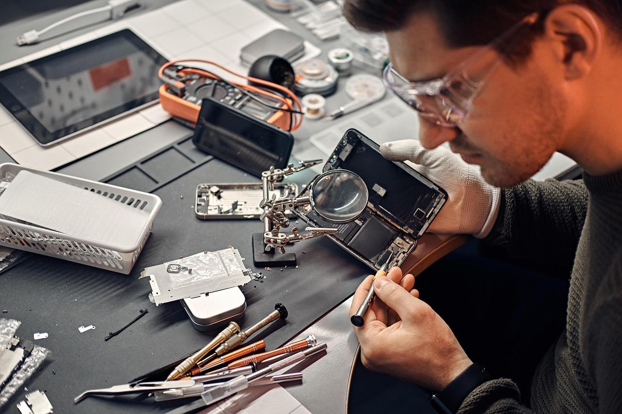 Technician repairing a smartphone in a workshop, representing expert device repair services.