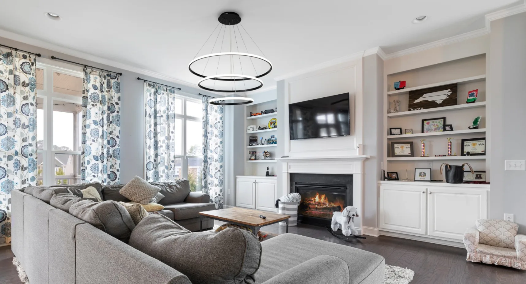 Sala de estar com pé-direito alto decorada com lustre Armor de 3 anéis suspenso