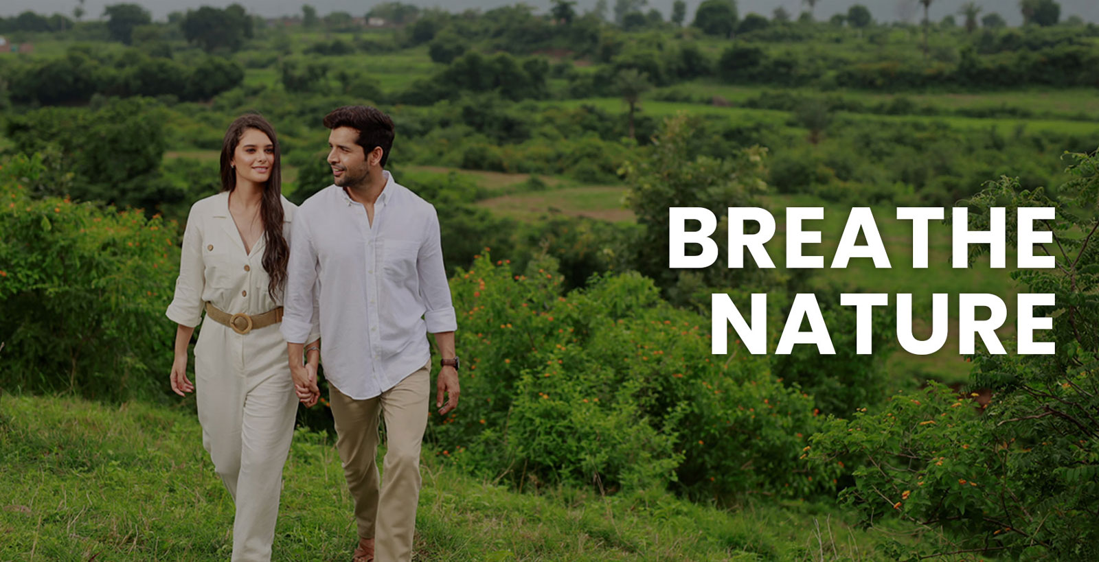 DLF Privana West — couple walking through greenery (marketing banner)