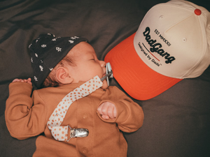 a baby laying on top of a bed next to a hat