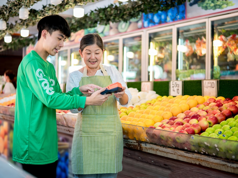 a man and a woman standing in front of a fruit stand
