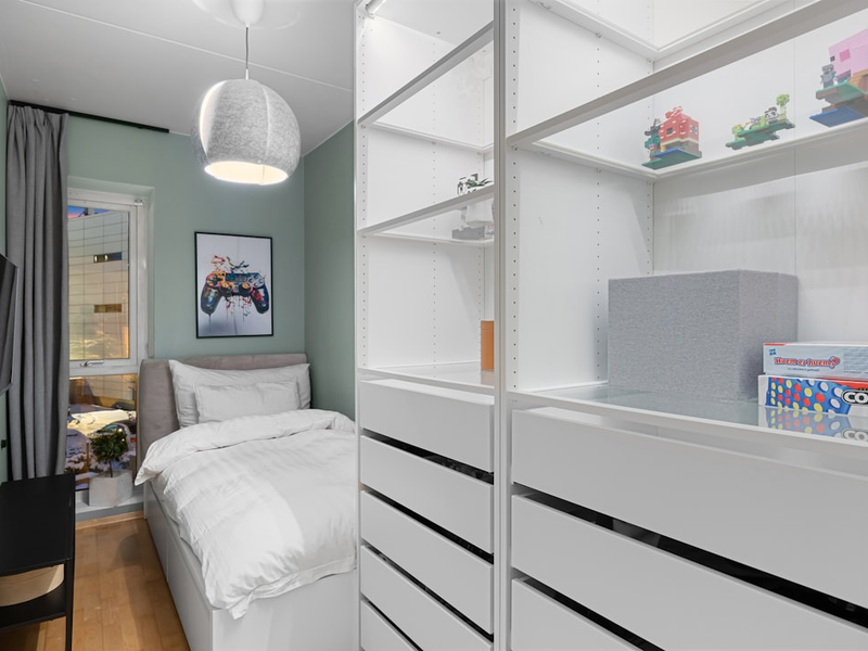 A room with a bed, desk, and shelves