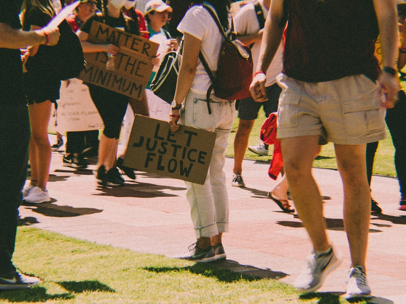 a group of people standing on a sidewalk holding signs