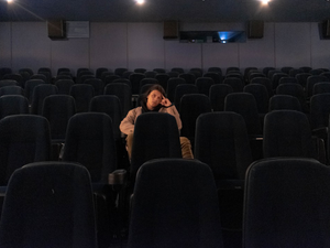 a man sitting in a movie theater talking on a cell phone