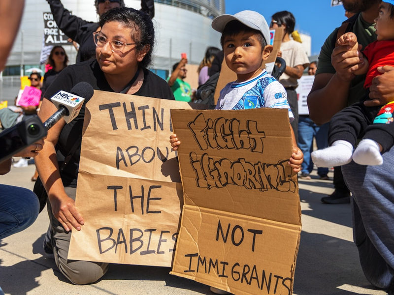Protestors hold signs about babies and immigrants.