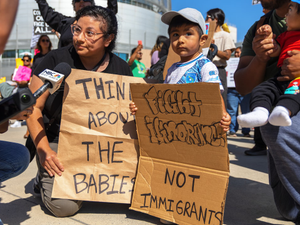 Protestors hold signs about babies and immigrants.