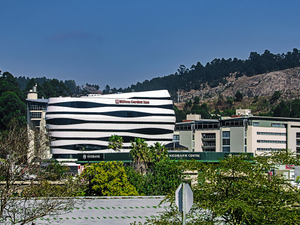A modern building stands against a backdrop of mountains.