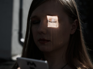 a woman with her eyes closed looking at a tablet