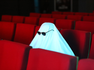 a ghost sitting in the middle of a row of red seats