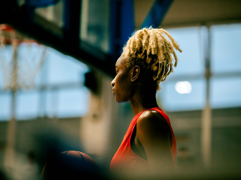 A woman with dreadlocks standing in front of a basketball hoop