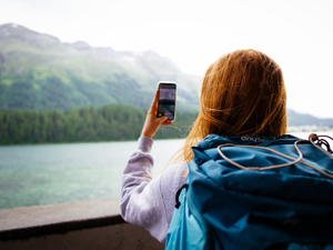 Young woman traveling, exploring and taking a photo of the Swiss alps while during Interrail