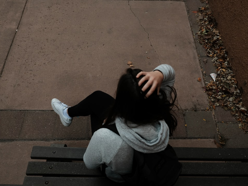 a person sitting on a bench on a sidewalk