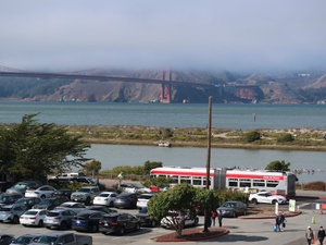 a red and white bus parked in a parking lot next to a bridge