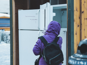 person in purple hoodie standing near white top mount refrigerator