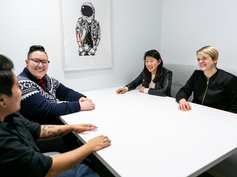 Group of people sitting around a white boardroom table. Mapbox Uncharted ERG (mapbox.com/diversity-inclusion) created these images to encourage and enable everyone in tech to represent LGBTQIA+ people at work, including collaboration and teamwork, leadership, design, engineering, and mobile development. These photos are free for anyone to use, as long as the use contains attribution to Mapbox. For more information see bit.ly/QueerTechPhotosAnnounce. For the full collection visit https://bit.ly/3chojW5
