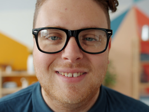 portrait of attractive young man in trendy glasses smiling laughing looking at camera indoors in apartment. Emotions, youth and stylish people concept.