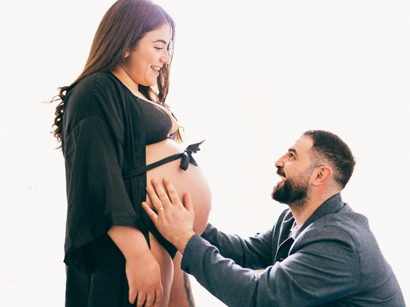 a pregnant man holding his pregnant wife's belly
