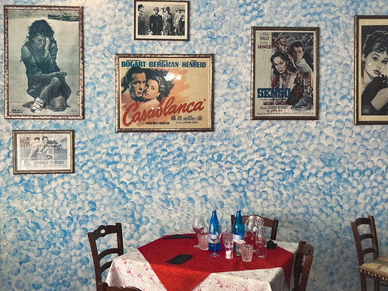 a table with a red tablecloth and chairs with pictures on the wall