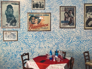 a table with a red tablecloth and chairs with pictures on the wall