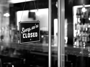 sorry, we're closed signboard hanging on glass door