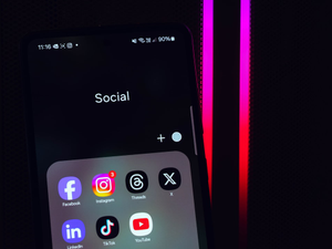 The Samsung Galaxy A52s with Android 13 and One UI 6.0 cointaing a folder with the most popular social media apps, including Facebook, Instagram, Threads, X/Twitter, LinkedIn, TikTok, and YouTube. Behind is my gaming PC with the BeQuiet Pure Base 500DX.