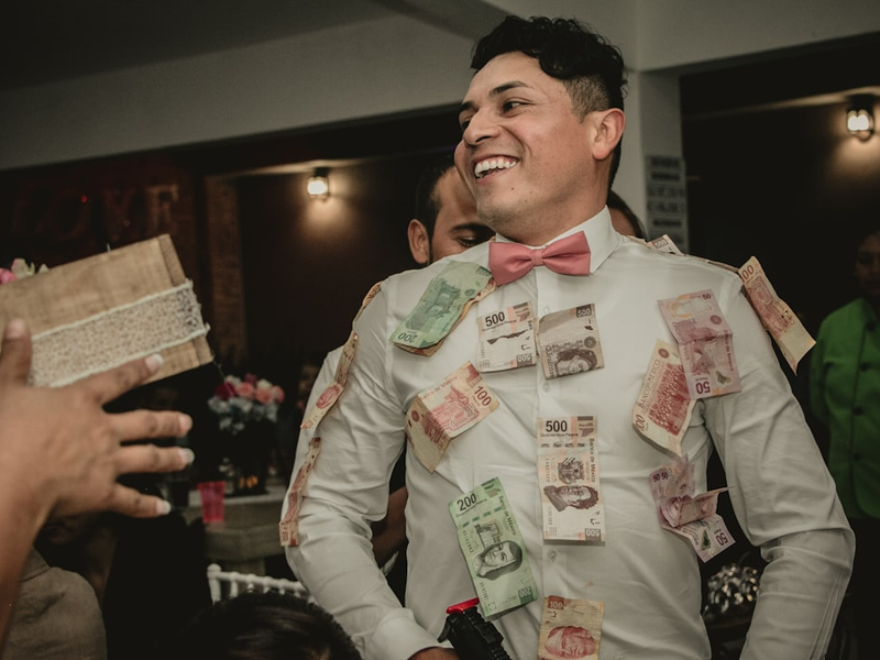 man wearing white formal suit with banknotes hanging