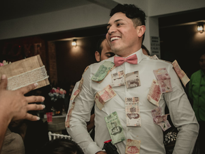 man wearing white formal suit with banknotes hanging