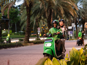 a couple of people riding on the back of a green scooter
