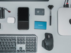 a desk with a keyboard, mouse, cell phone and other items