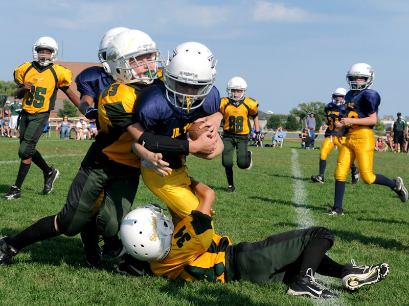football players struggling to hold the football during daytime