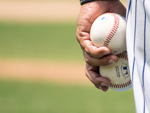 man holding two white baseballs