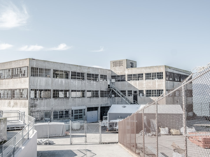 white concrete building front of iron wire fence at daytime