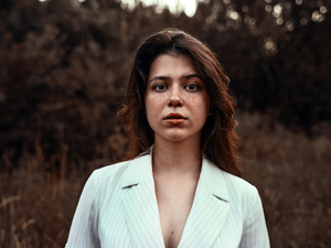 a woman in a white suit standing in a field
