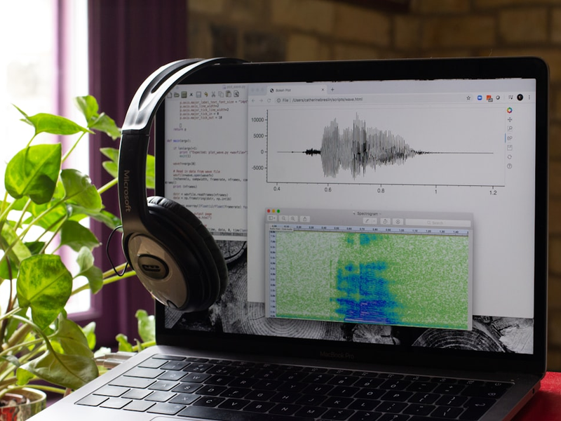 A computer showing sound files open with some computer code and headphones