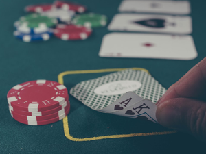 person holding black ace and king spades playing cards on poker table
