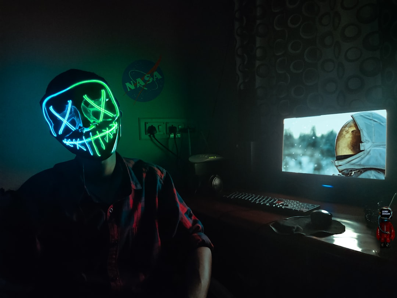 Person wearing Led Mask sitting in front of computer.