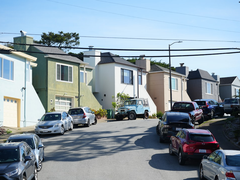 Cars parked on a residential street with houses.