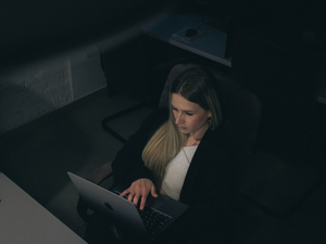 Woman working late on a laptop in a dark office.