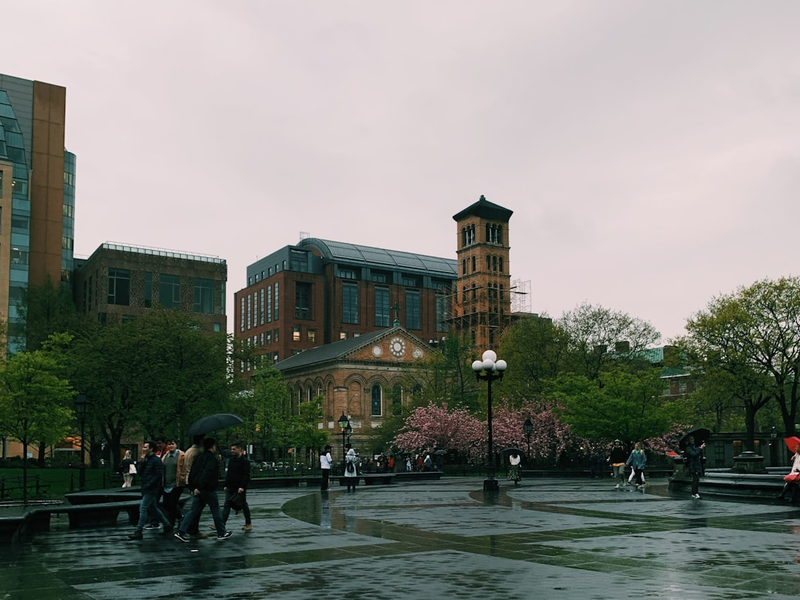 people walking near road beside concrete houses