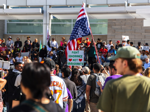 Protesters wave flags at an outdoor gathering.