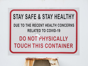Warning sign saying "Stay safe & stay healthy / Due to the recent health concerns related to covid-19 / Do not physically touch this container"