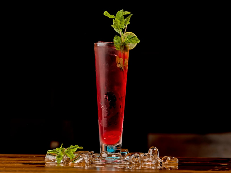 a tall glass filled with a drink and garnished with mint