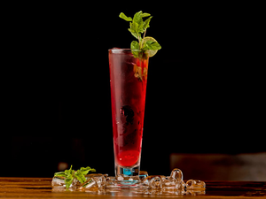 a tall glass filled with a drink and garnished with mint