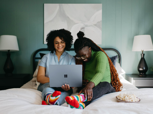 a woman sitting on a bed using a laptop