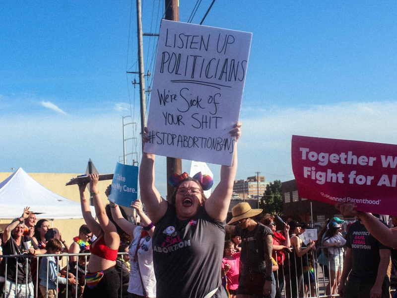 woman raising listen up politicians sign on road