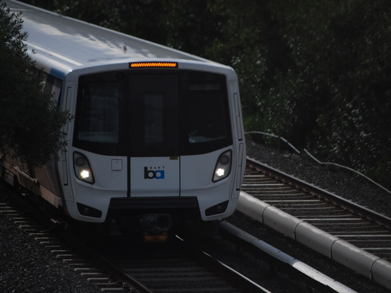 a white train traveling down train tracks next to a forest