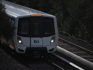 a white train traveling down train tracks next to a forest