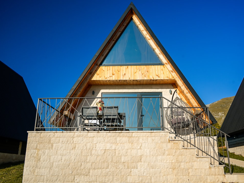 Wooden triangular cabin surrounded by nature, showcasing rustic charm and cozy architecture.